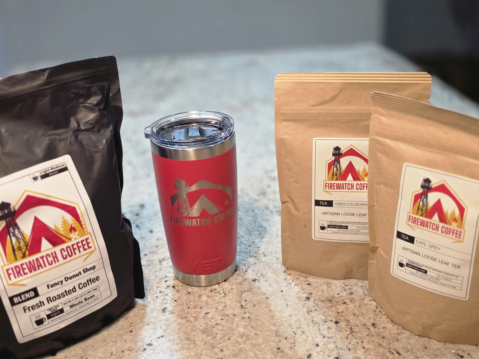 FireWatch coffee and tea bags beside a red branded tumbler, photographed from our collection